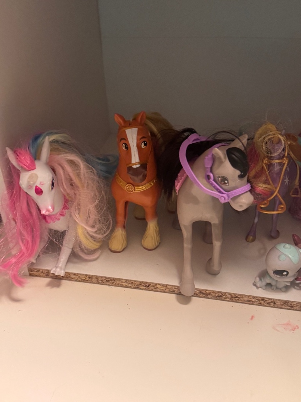 Set of colorful kids pony toys. Features pink-and-white unicorn, brown horse, an